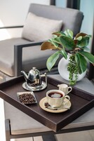 Een dienblad met een koffiepot, kop en schotel op een tafel, een kom met koffiebonen en een potplant.