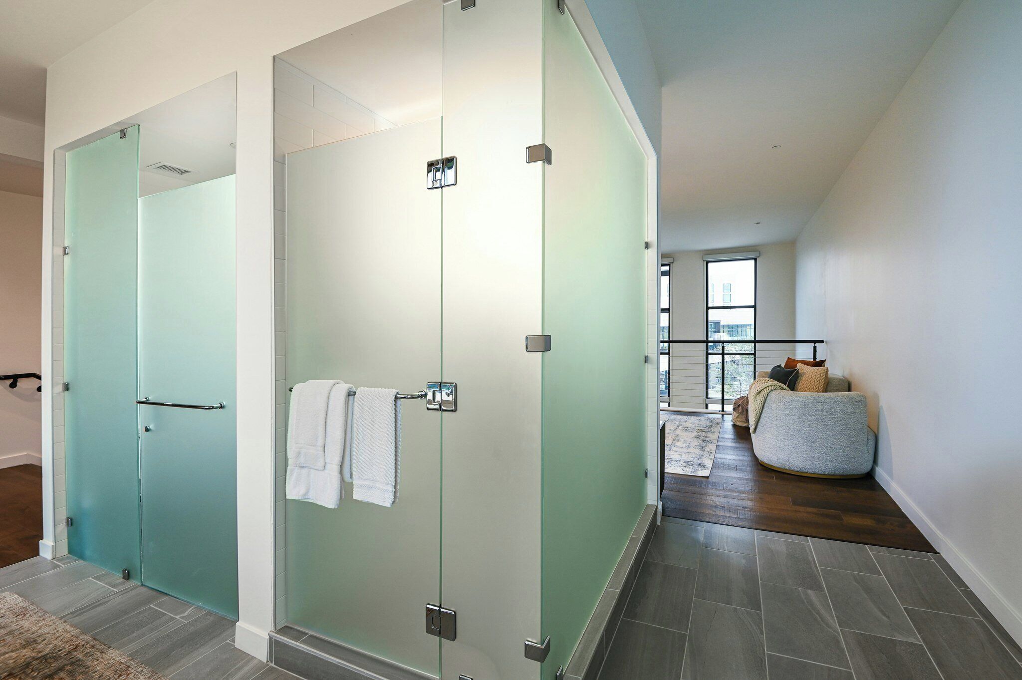 Une salle de bain moderne avec des portes en verre dépoli, un porte-serviettes et un espace douche bien délimité.