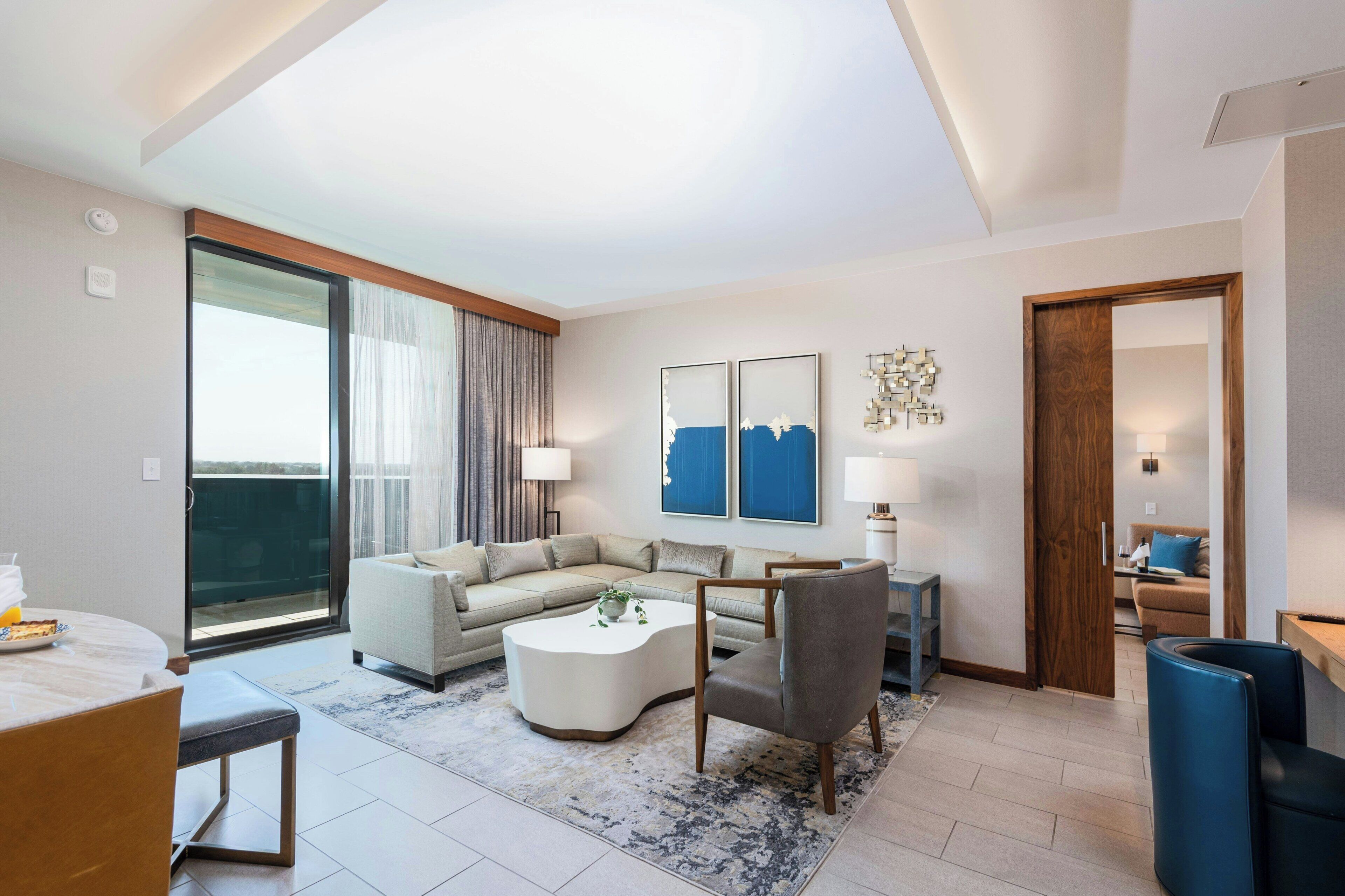 Una sala de estar moderna con un sofá, sillones, una mesa de centro y un comedor con mesa y sillas.