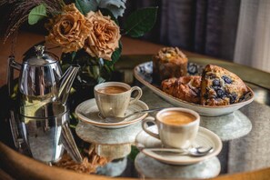A tray with two cups of coffee, a teapot, and a plate of muffins.