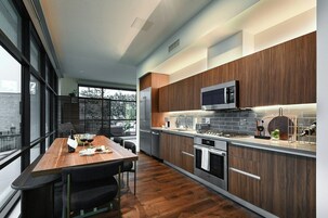Una cocina moderna con armarios de madera, electrodomésticos de acero inoxidable y un comedor con mesa y sillas de madera.