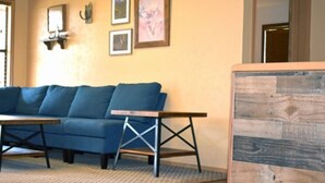 Una habitación con un sofá azul, una mesa de madera y una alfombra estampada.