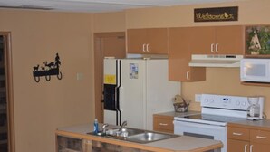 Una cocina con una isla de madera, un refrigerador, un microondas y armarios.