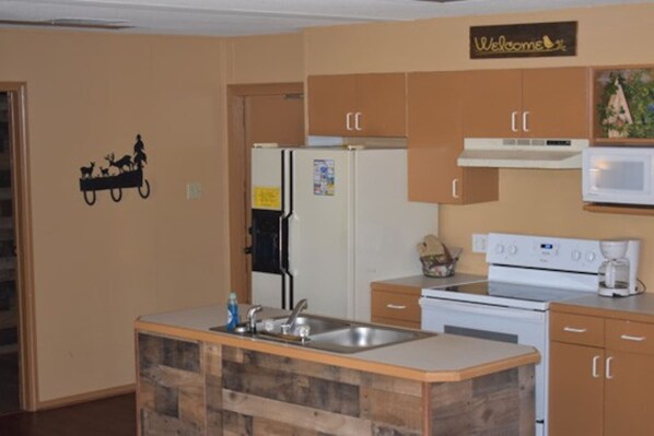Una cocina con una isla de madera, un refrigerador, un microondas y armarios.