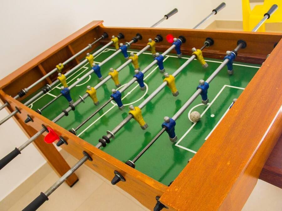 A foosball table with a wooden frame and a green playing surface.