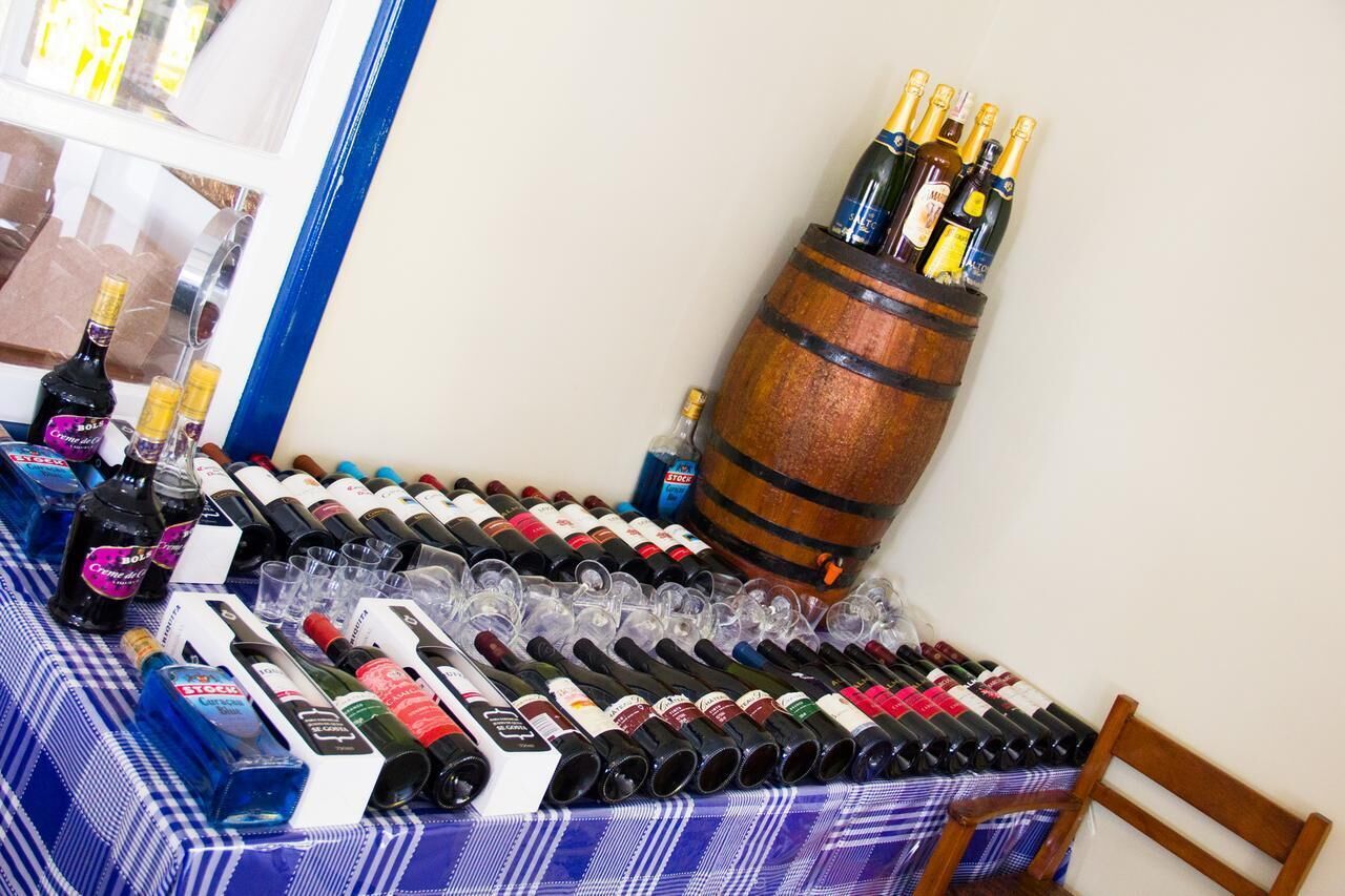 A table with various bottles and glasses of wine, a wooden barrel, and a checkered tablecloth.