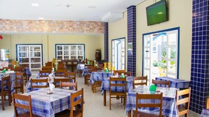Un restaurant doté de nombreuses tables et chaises, de murs carrelés et d’un téléviseur fixé au mur.
