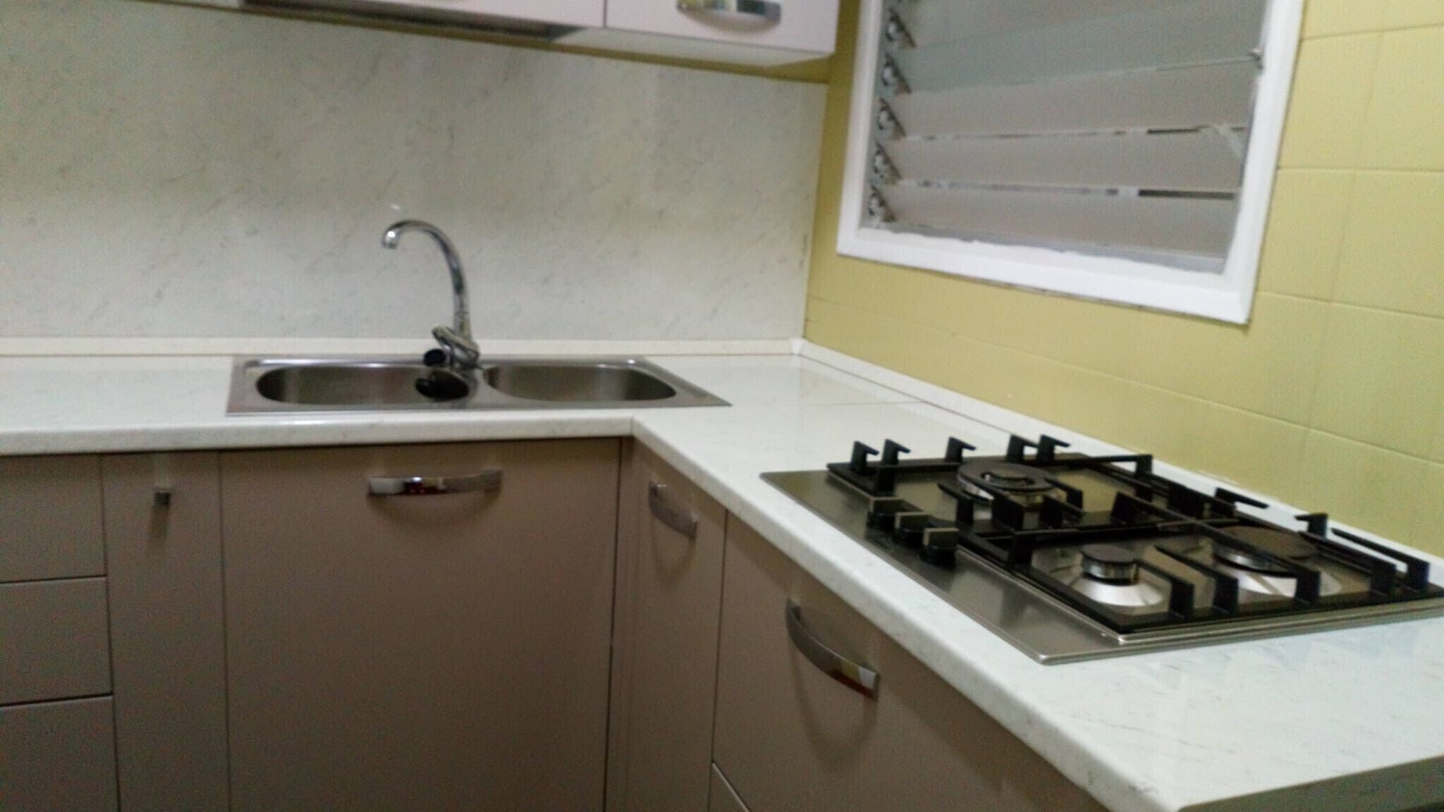 A kitchen with a sink, cabinets, and a gas stove.