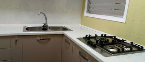 A kitchen with a sink, cabinets, and a gas stove.