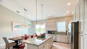 A modern kitchen with a large island, white cabinets, and stainless steel appliances. - Pet-Friendly Island Home | Pool, Hot Tub + Cart (Upper Captiva)