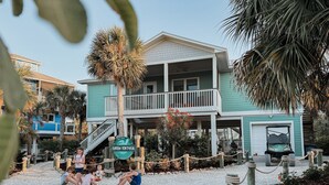A beachfront property with a two-story building, a covered patio, and a sign indicating 'Green Tortooga'. - Pet-Friendly Island Home | Pool, Hot Tub + Cart (Upper Captiva)
