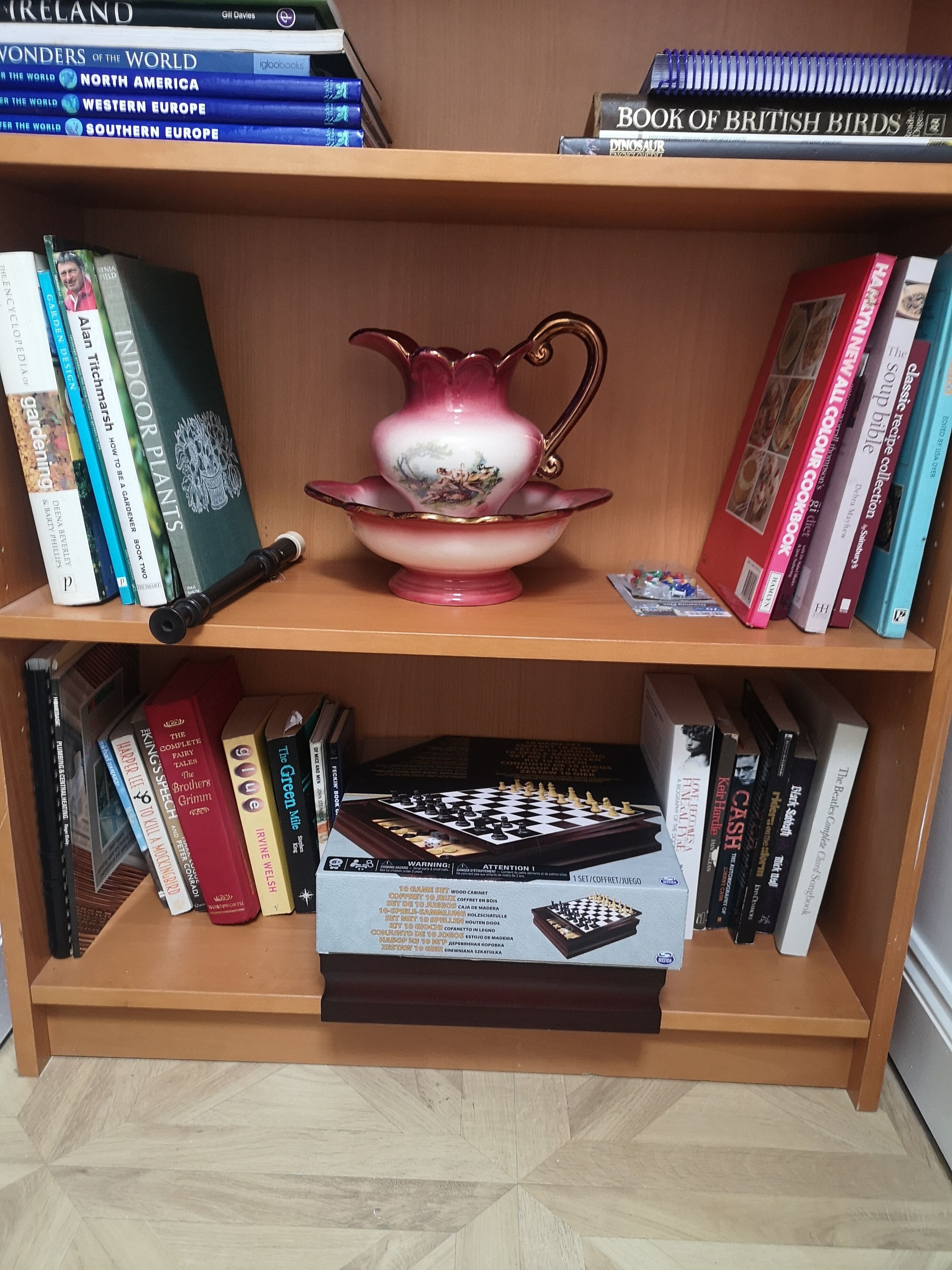 Una estantería con libros y una jarra decorativa.