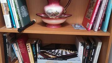 Una estantería con libros y una jarra decorativa.