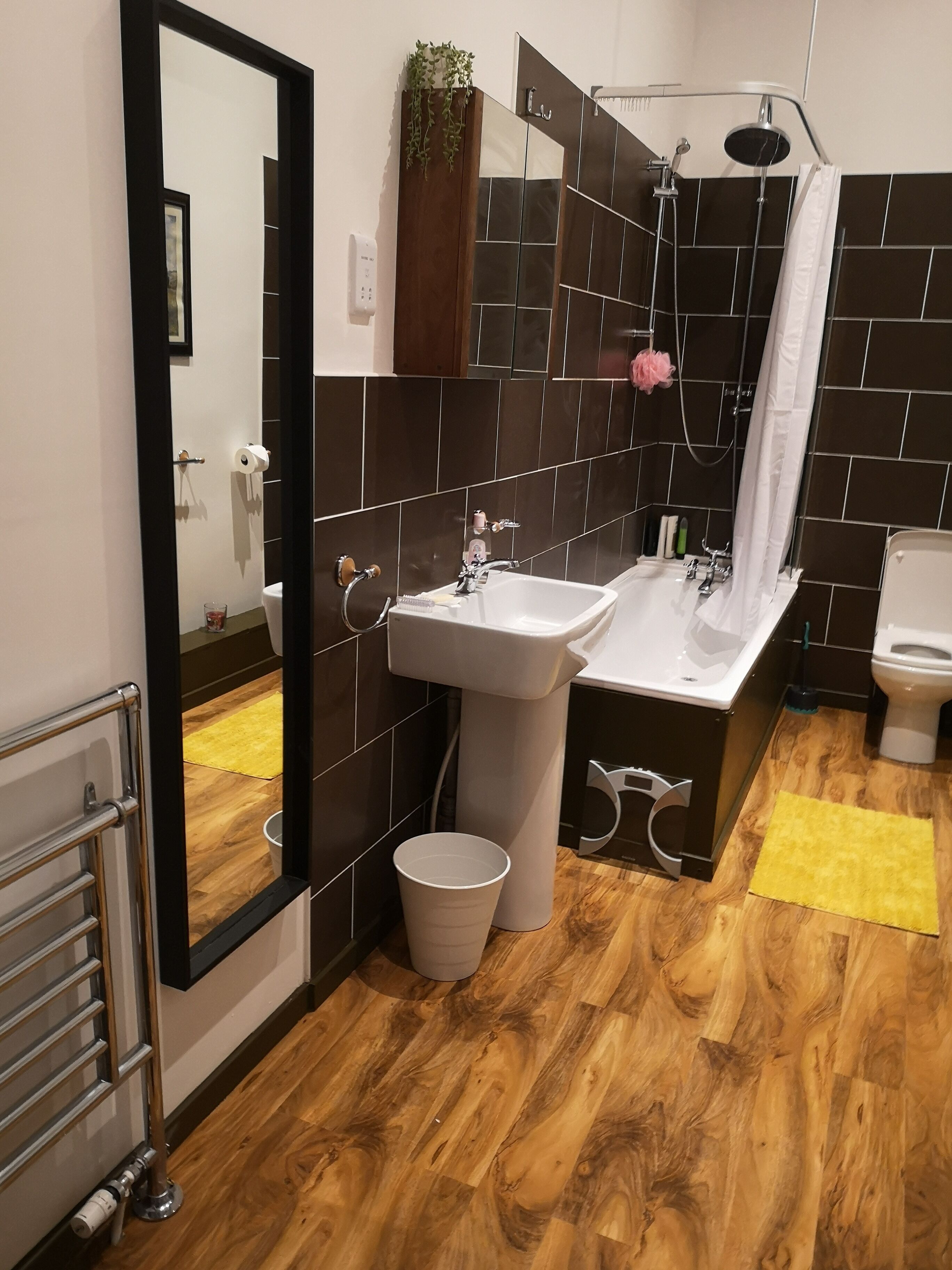 Un baño moderno con un espejo grande, un lavamanos, una ducha y un inodoro.