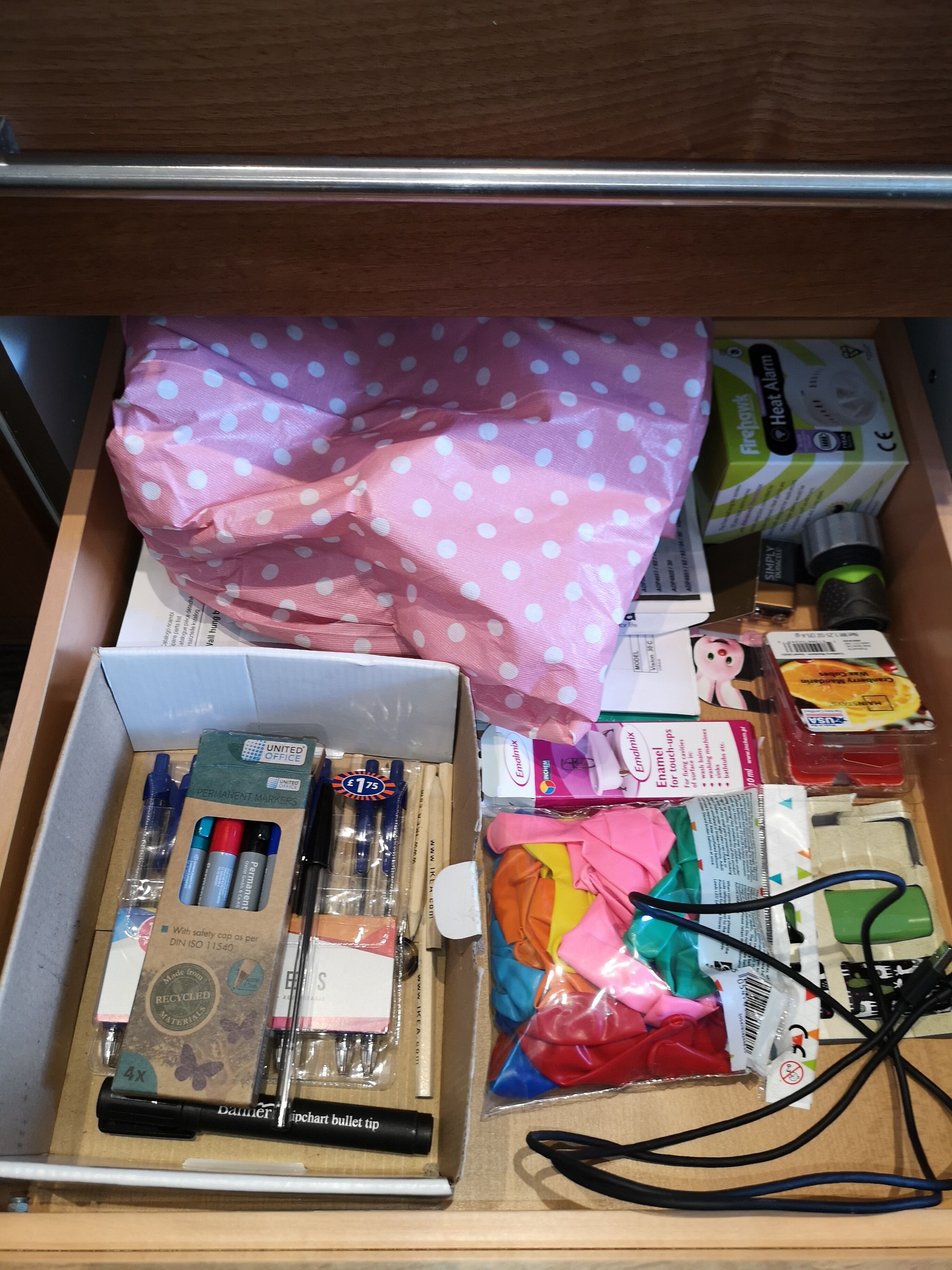 Un tiroir contenant du matériel de bureau, notamment des marqueurs, des stylos et une agrafeuse.