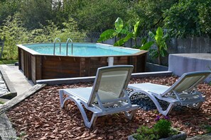 Relax in a serene hot tub surrounded by lush greenery and comfortable lounge chairs.