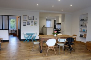 Enjoy meals in this dining area with a wooden table and chairs, surrounded by framed pictures and a potted plant.