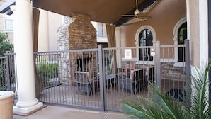 A gated patio area with a stone fireplace, outdoor seating, and a sign indicating the gate is closed and locked at all times.