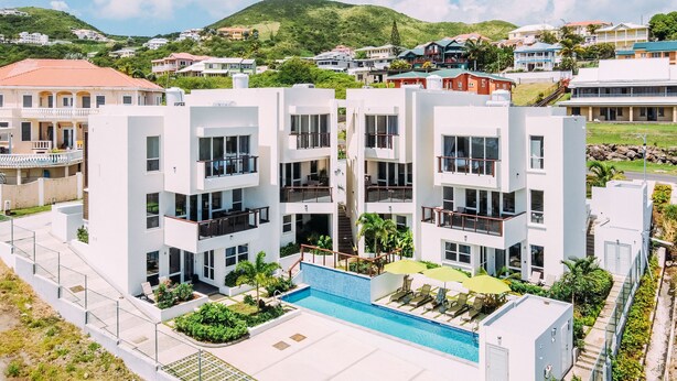 A modern multi-story building with a swimming pool, balconies, and a landscaped garden. - #3-2BR Shalimar Vacation Townhouse, Frigate Bay, Saint Kitts. (Basseterre)