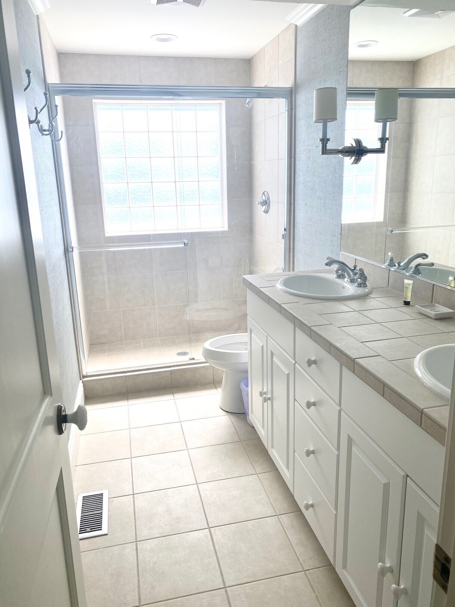 Une salle de bain moderne équipée d’une douche, de toilettes et de deux lavabos.