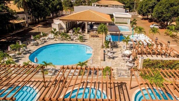 A resort with a large central pool, smaller adjacent pools, and a covered area with umbrellas. - Apartamento de 2/4 no Resort Internacional (caldas novas)
