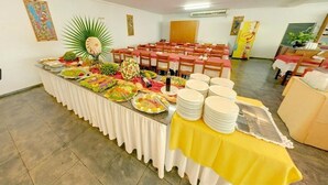 A buffet setup with various food items and stacked plates. - Apartamento de 2/4 no Resort Internacional (caldas novas)
