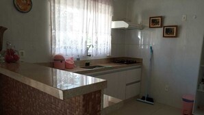 A kitchen with a marble countertop, a sink, a stove, and a window with curtains. - Apartamento de 2/4 no Resort Internacional (caldas novas)