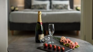 Een bed in een hotelkamer met een fles champagne en een glas op een bijzettafeltje.