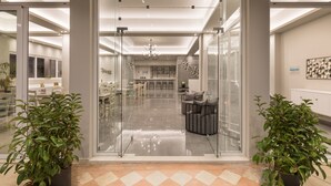 Een modern interieur met een glazen deur, een eetgedeelte en een keuken met een kroonluchter.