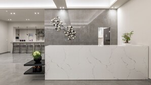 Een moderne receptie met een marmeren balie, een wandlamp en een potplant.