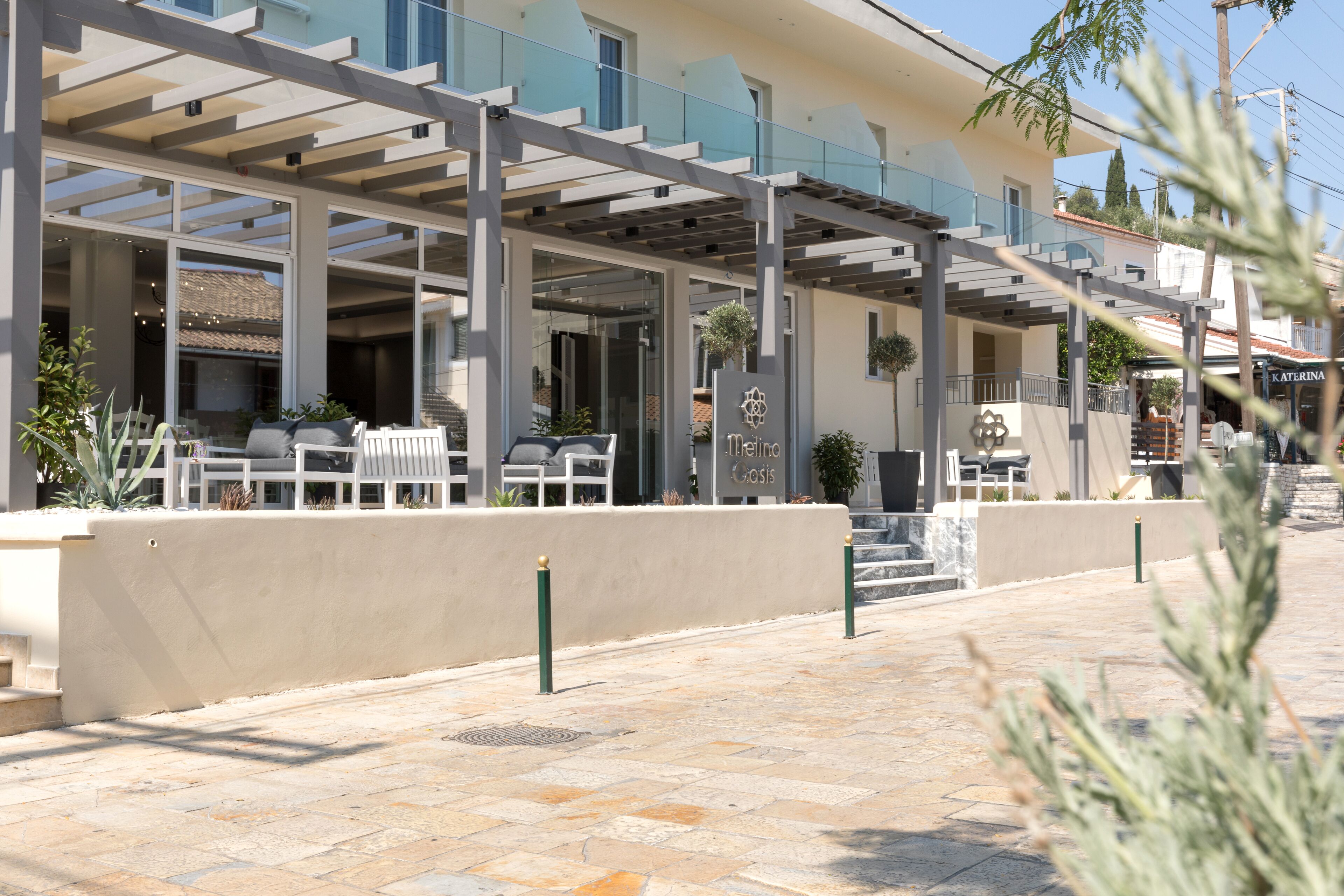 A modern outdoor seating area with tables and chairs, a covered patio, and a building with a sign reading "Hotel".