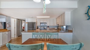 Una cocina moderna con armarios blancos, una isla central y un comedor con dos sillas.