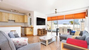 A modern living room with a sofa, a coffee table, and a dining area with chairs.