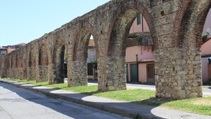 A row of stone arches with a paved street in front. - Camera VENERE (Pisa)