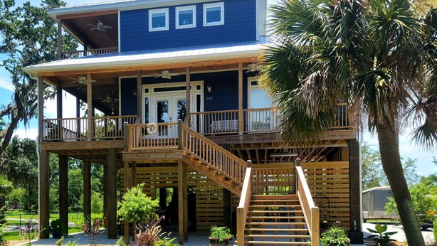 Une maison à deux étages avec une terrasse en bois, un escalier et un balcon.