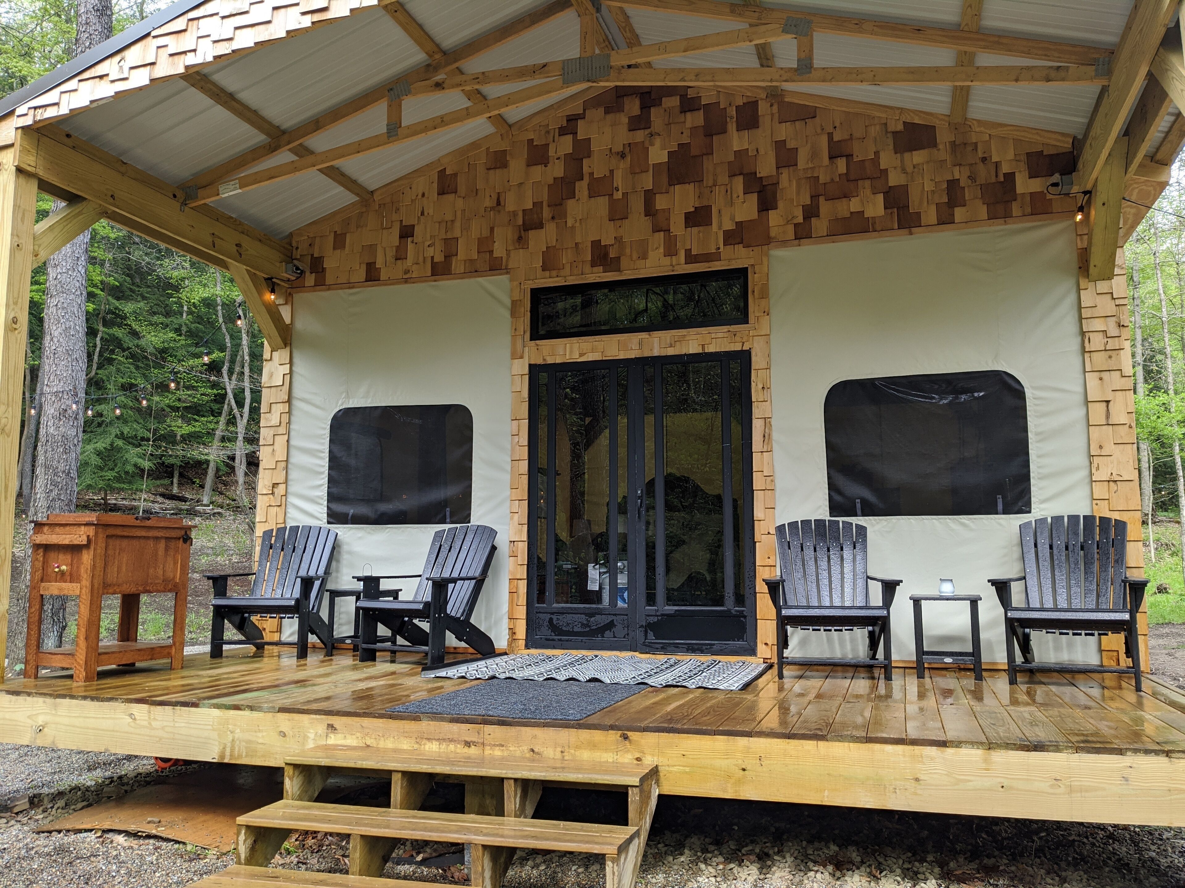 Une terrasse en bois avec quatre chaises Adirondack, une petite table et un banc.
