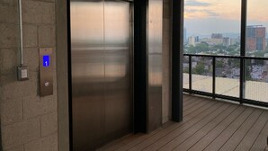 An elevator with a digital display indicating floor 1, a metal door, and a view of a cityscape through large windows. - New Apartment with Amazing Decoration (Guadalajara)