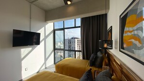 A hotel room with two beds, a flat-screen TV, a large window with a city view, and a ceiling fan. - New Apartment with Amazing Decoration (Guadalajara)