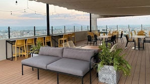 A rooftop terrace with a sofa, chairs, tables, and string lights. - New Apartment with Amazing Decoration (Guadalajara)