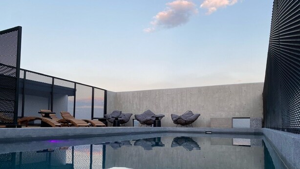 A modern rooftop pool with clear reflections, lounge chairs, and a concrete wall. - New Apartment with Amazing Decoration (Guadalajara)
