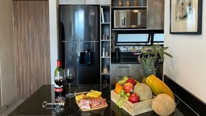 A modern kitchen with a refrigerator, microwave, and a fruit basket on the counter. - New Apartment with Amazing Decoration (Guadalajara)