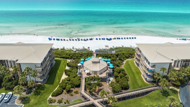 Un resort con vista a la playa, varias piscinas y un césped bien cuidado.