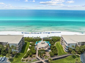 Un resort con vista a la playa, varias piscinas y un césped bien cuidado.