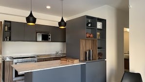 Una cocina moderna con una isla central, muebles oscuros e iluminación colgante.