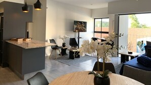 Un espacio habitable moderno con isla de cocina, zona de estar y balcón con vistas.