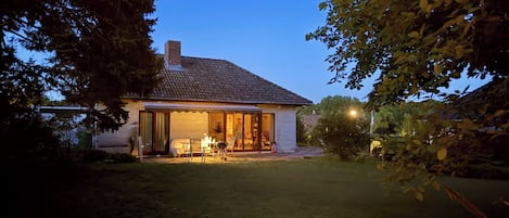 A house with a tiled roof, a visible chimney, and a covered patio area with outdoor furniture.