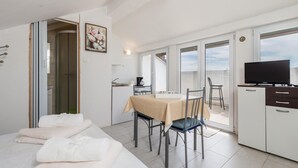Una habitación de hotel moderna con cama, mesa de comedor, televisor y balcón con vistas.