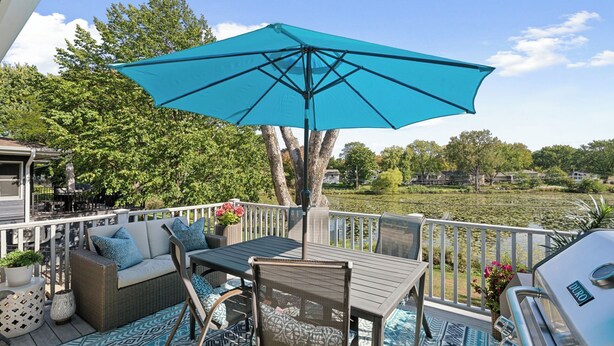 A deck with outdoor furniture, a grill, and a view of a lake. - Brand New WATERFRONT Listing! (Bloomington)