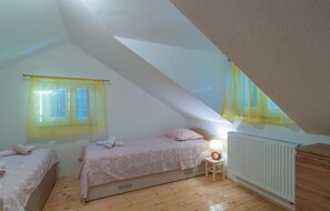 A small attic bedroom with two beds, a radiator, and a small table with a lamp. - Beautiful home in Postira (Postira)