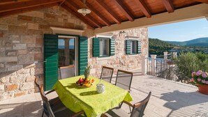 A stone building with a balcony, green shutters, and a table with fruit. - Beautiful home in Postira (Postira)